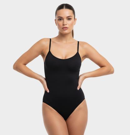 professional 1:1 studiofoto van dezelfde vrouw. geen verandering in gezicht of lichaam. real skin texture. real pores. natural imperfections. dunne schouderbandjes. shapewear bodysuit thong in kleur #000000. smooth matte 4D stretch. clean white studio. direct eye contact. pose handen in de zij lichte heupshift. powerful confident. MODEL. Light medium huid, ponytail, 24 jaar, elegant luxe uitstraling.
