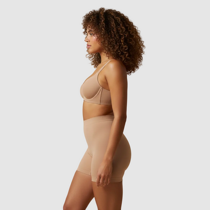 Studio photo, same female model, 28 years old, vol tan skin, tight natural curls. Wearing nude high-waisted sculpt shorts and matching bra. Side view. High-waisted sculpt shorts ending mid-thigh, approx 8–10 cm above the knee, straight hem. Emphasis on waist and hip curve. Clean light beige background. Ultra realistic. 800x800.