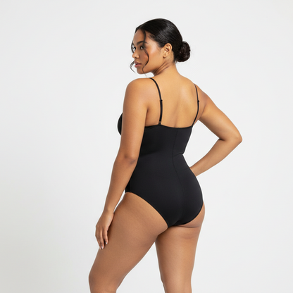 Zwart achterkant
Professional 1:1 studiofoto van dezelfde vrouw. Geen verandering in gezicht of lichaam. Real skin texture. Natural imperfections. Dunne schouderbandjes. Shapewear bodysuit in zwart. Clean white studio. Zachte schaduw. Pose back view met één hand in de zij en hoofd licht gedraaid naar camera. Curvy. Bruine huid. Low bun. 26 jaar.